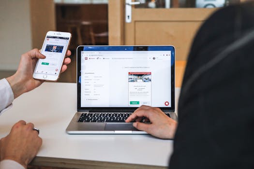 Hands using a smartphone and laptop to browse job listings